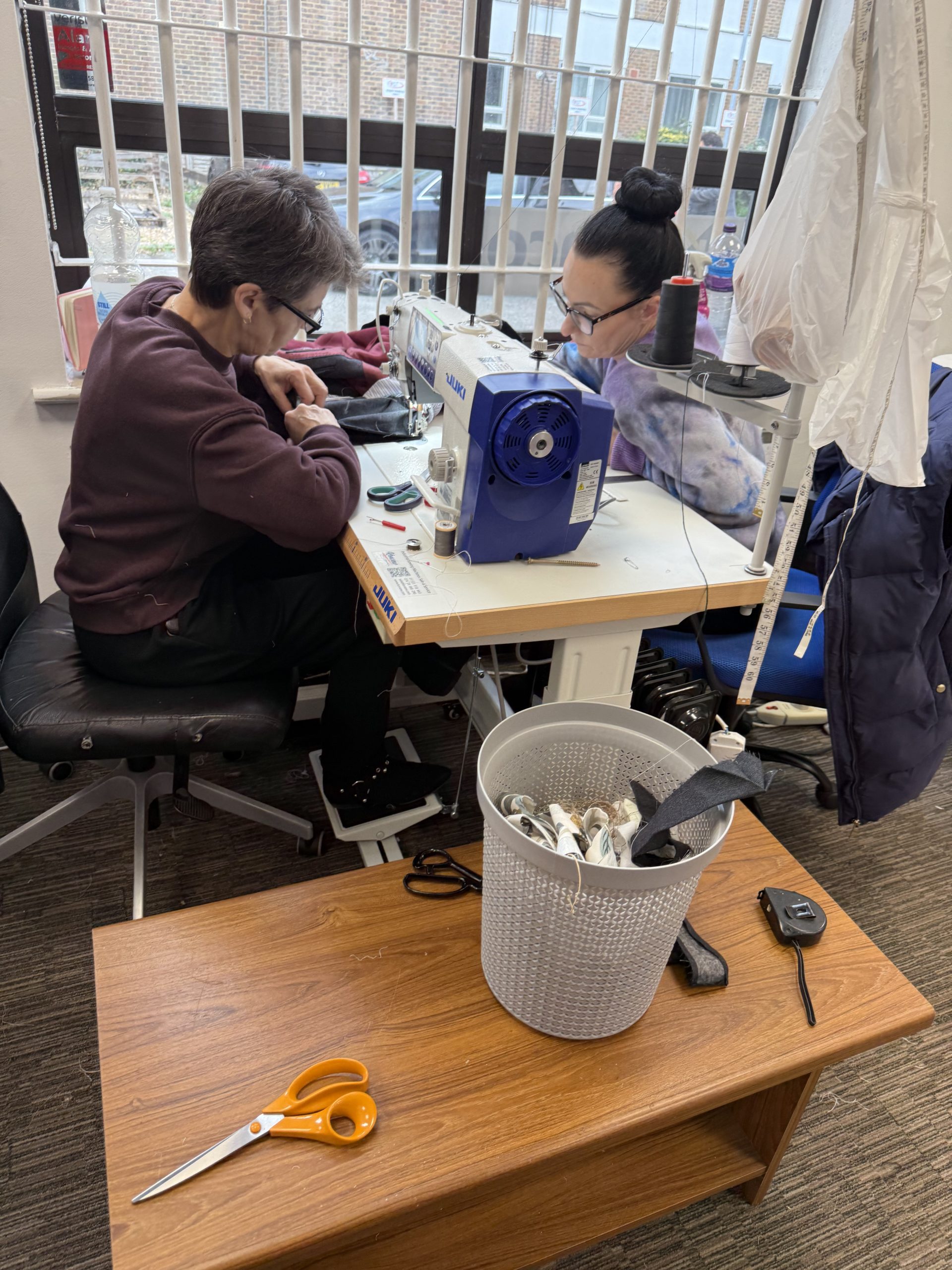 Two MK Seamstress team members working together on a jacket alteration in the Bletchley sewing studio.